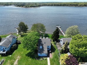 A residential area with houses near a large body of water, a dock, and a small boat.