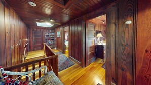 A wooden interior with a staircase, a rug, and a desk with a lamp. - Gorgeous Waterfront Home in the Heart of North Kingstown (North Kingstown)
