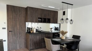 Una cocina moderna con armarios de madera oscura, una isla central con un lavamanos y un comedor con mesa y sillas.