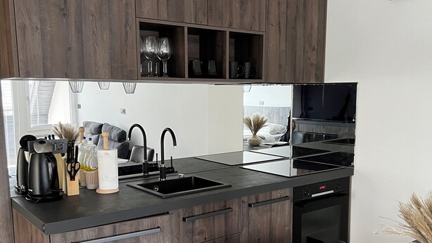 Una cocina moderna con armarios de madera oscura, encimera negra y electrodomésticos de acero inoxidable.