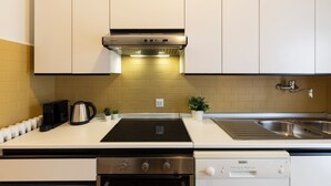 A modern kitchen with white cabinets, a black stove, a dishwasher, and a stainless steel sink. - notaMi - Feels Like Home (Milan)