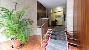 A staircase with a wooden handrail and a potted plant on the left. - notaMi - Feels Like Home (Milan)