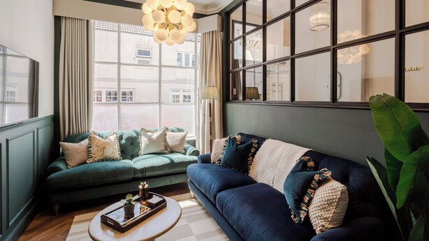A modern living room with a green sofa, a blue sofa, and a round coffee table. - The Clifton Residence (Bristol)