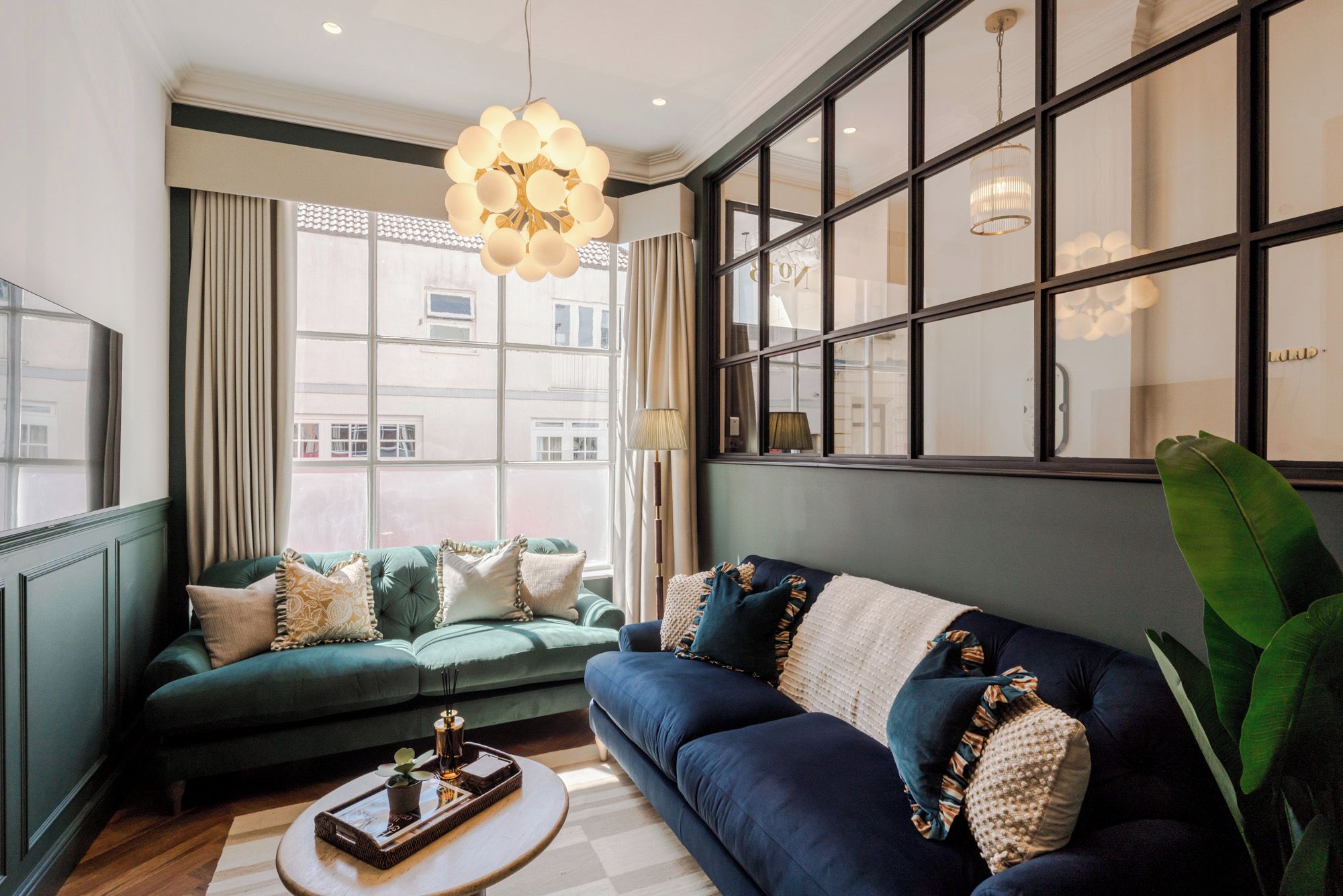 A modern living room with a green sofa, a blue sofa, and a round coffee table.