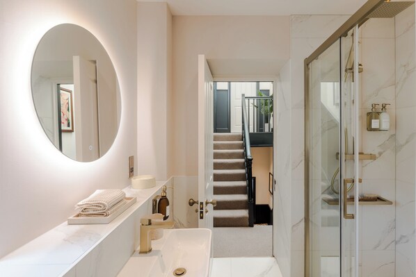 A modern bathroom with a large mirror, a bathtub, and a shower area.