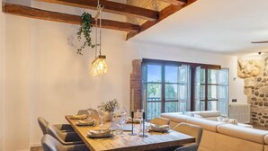 A dining area with a wooden table, chairs, and hanging plants. - Mansion 35min Madrid|Cinema| Pool|BBQ| Car Charger (Guadalajara)