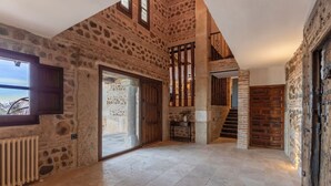 A spacious interior with stone walls, a large sliding glass door, and a staircase leading to an upper level. - Mansion 35min Madrid|Cinema| Pool|BBQ| Car Charger (Guadalajara)