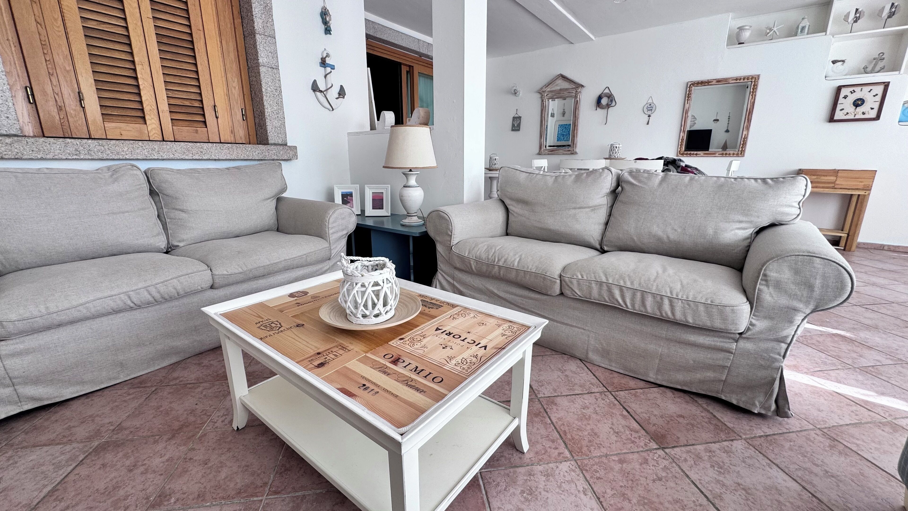 A living room with two grey sofas, a wooden coffee table with a decorative tray, and a white lamp.