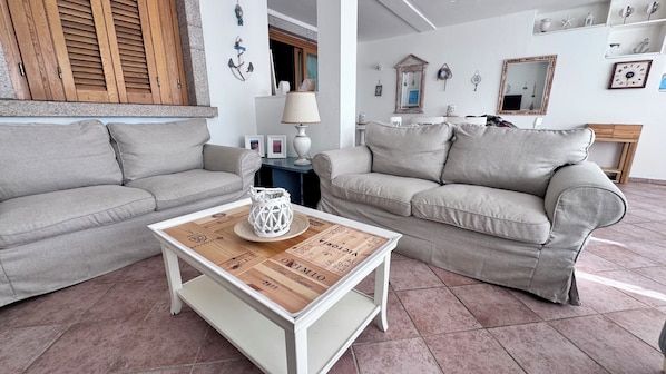 A living room with two grey sofas, a wooden coffee table with a decorative tray, and a white lamp.