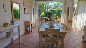 A dining area with a table and chairs, a mirror, and a window with curtains.