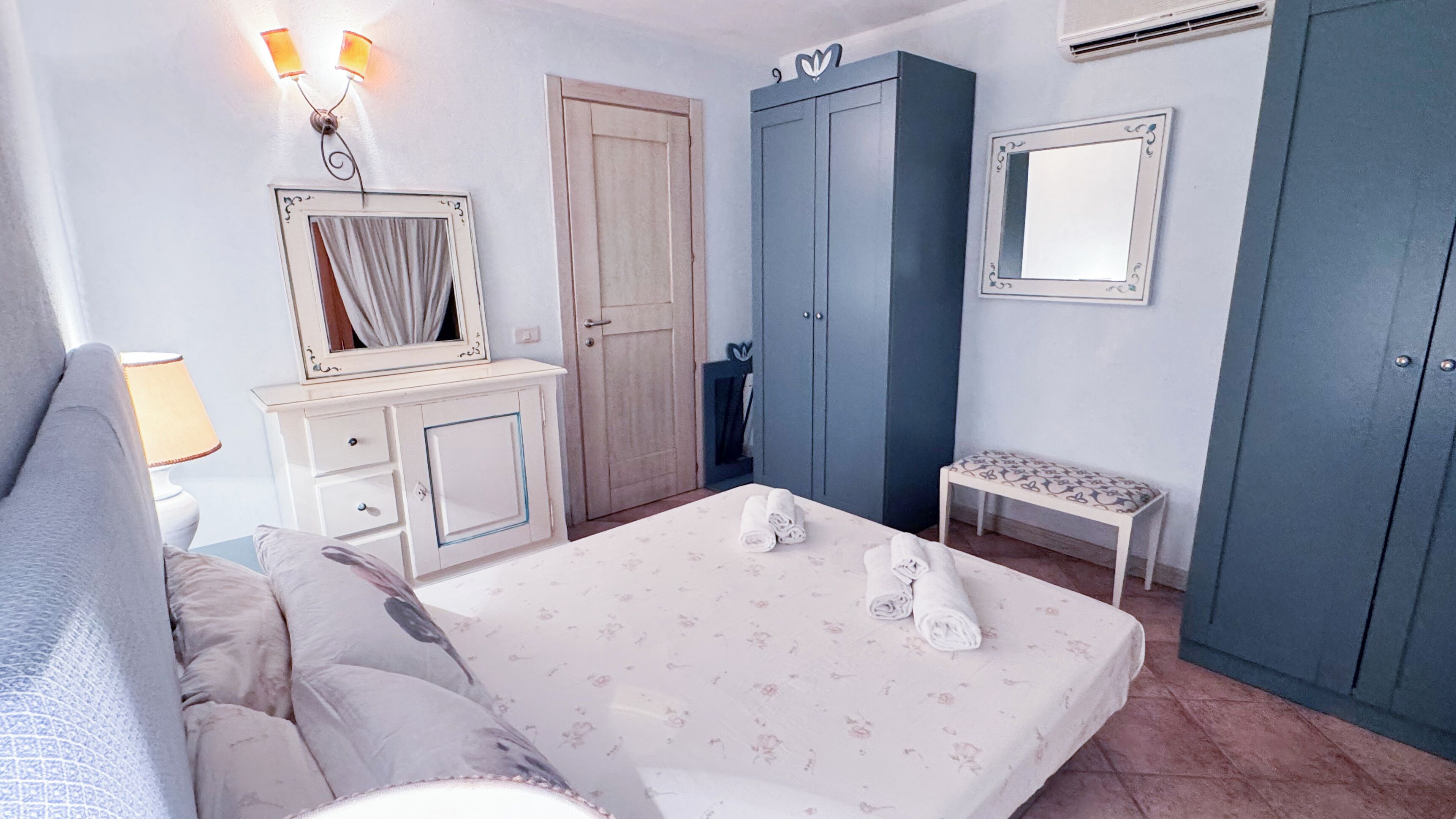 Un dormitorio con cama, cómoda, armario, mesita de noche y espejo.
