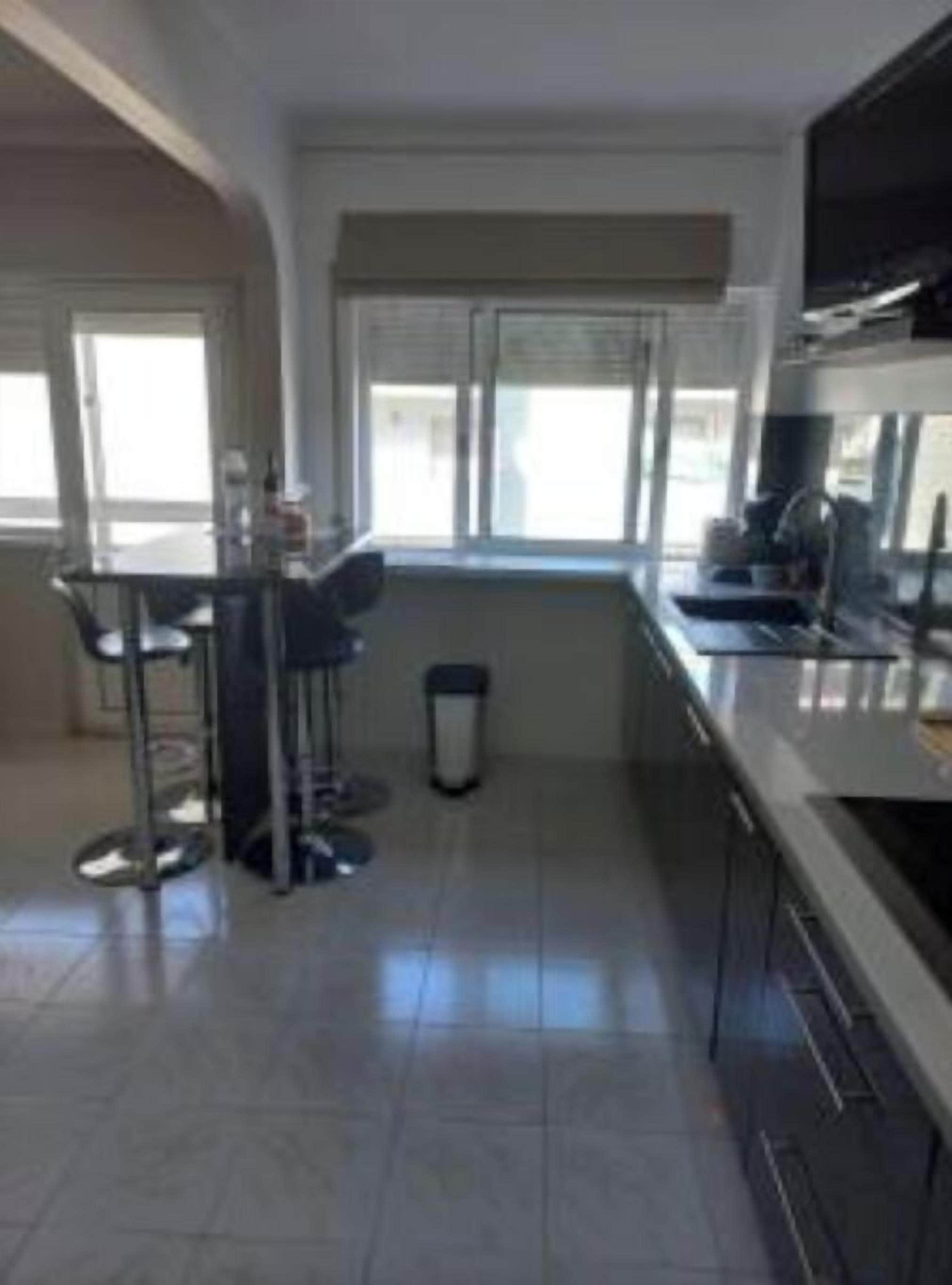 Una cucina moderna con zona pranzo, ampie finestre e un cestino.