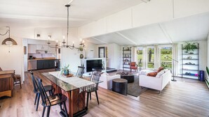 Ein geräumiger Wohnbereich mit Esstisch, Stühlen, einer Couch und einem Fernseher.