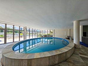 Una piscina cubierta, una piscina al aire libre, sombrillas, tumbonas