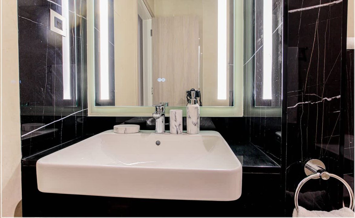 A modern bathroom with a large rectangular sink, a mirror, and a towel ring.