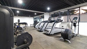Un gimnasio con cintas de correr, máquinas de pesas y un espejo grande.