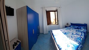 A bedroom with a bed, a wardrobe, a nightstand, and a window.