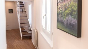 Ein Flur mit Holzboden, einer Treppe, einem Heizkörper und einem gerahmten Bild an der Wand.