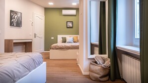 Ein Schlafzimmer mit einem Bett, einem Fenster mit Vorhängen, einem Heizkörper und einer Wand-Klimaanlage.