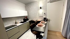 Een moderne keuken met een eethoek, met een zwarte eettafel, witte kasten en een inbouwoven.