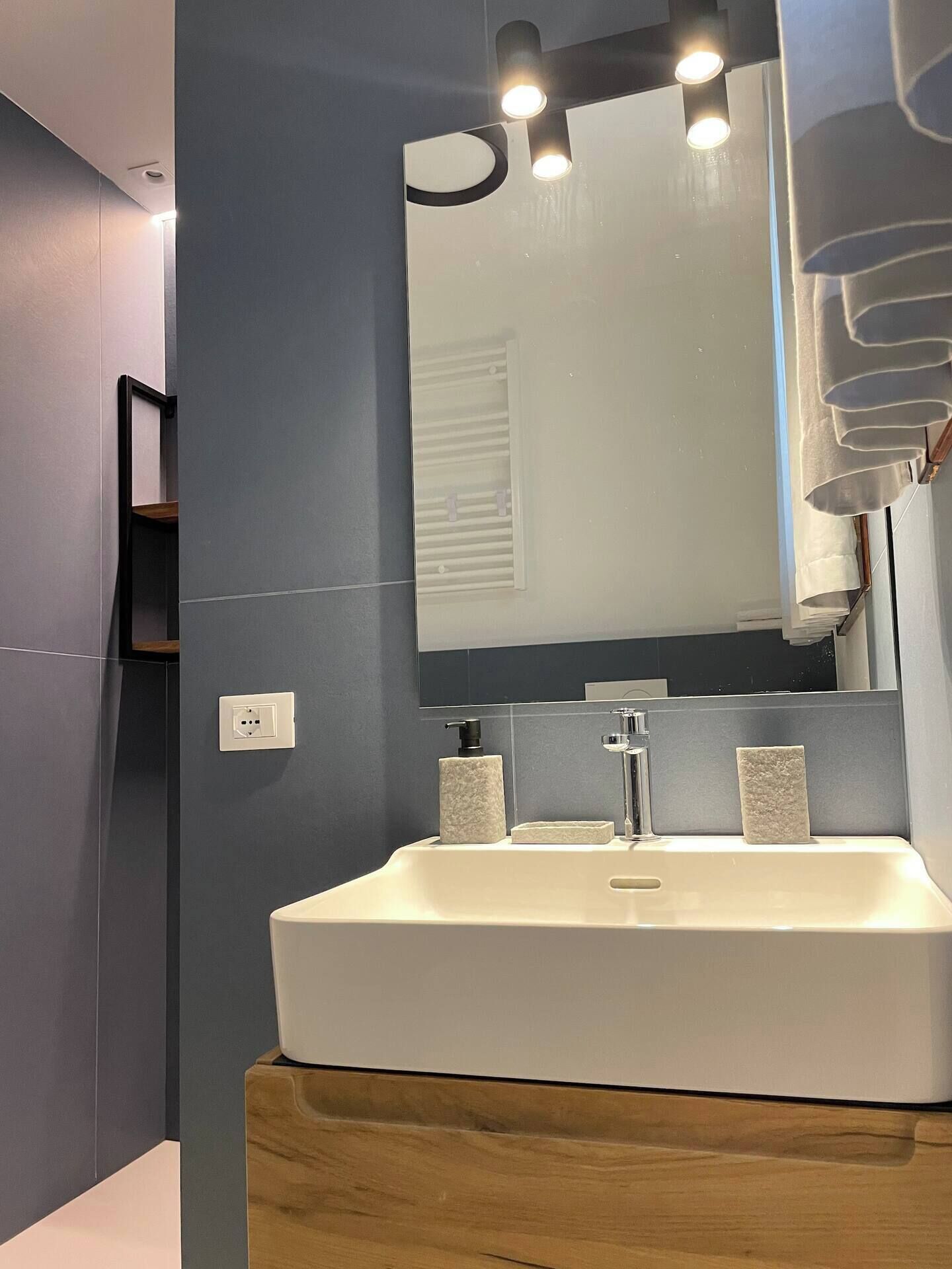 Ein modernes Badezimmer mit einem weißen Waschbecken, einem Spiegel und einem Holzwaschtisch.