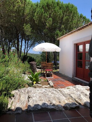 An outdoor patio with a white umbrella, a wooden table and chairs, and a stone wall. - Casal da Serrana (Lourinhã)