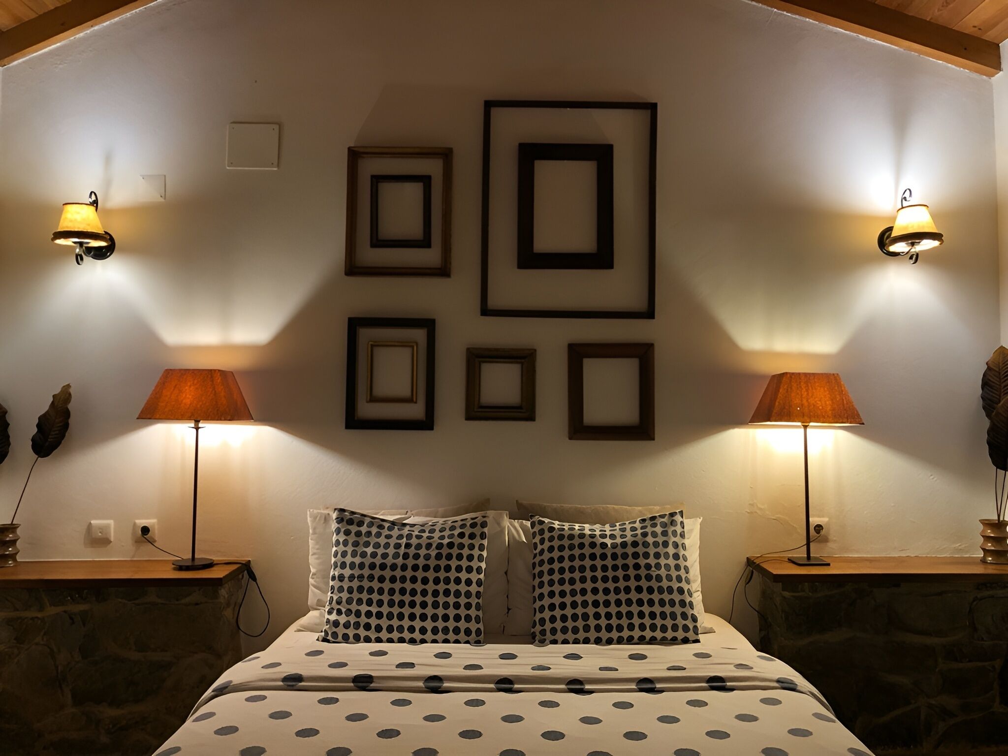 Un dormitorio con una cama, dos mesitas de noche y lámparas de pared.