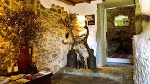 Un intérieur rustique avec des murs en pierre, un plafond en bois et une cheminée en pierre.