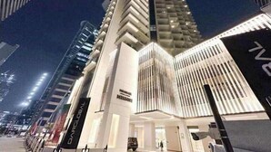 Un hotel moderno con una entrada destacada en esquina, grandes ventanales y fachada limpia y blanca.