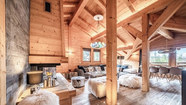 A spacious wooden cabin with a high ceiling, a fireplace, a cozy seating area, and a dining table. - Solstice - Spacious Alpine Apartment Les Gets (Les Gets)