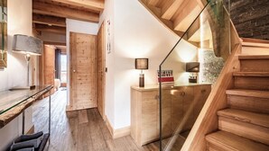 A modern interior with a wooden staircase, a glass door, and a kitchen area with wooden cabinets. - Solstice - Spacious Alpine Apartment Les Gets (Les Gets)