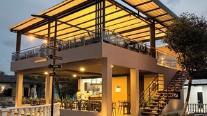 A two-story building with a covered patio, outdoor seating, and a staircase leading to the upper level.