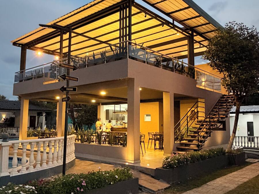 A two-story building with a covered patio, outdoor seating, and a staircase leading to the upper level.