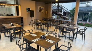 A restaurant with multiple tables and chairs, a bar area, and a staircase leading to an upper level.