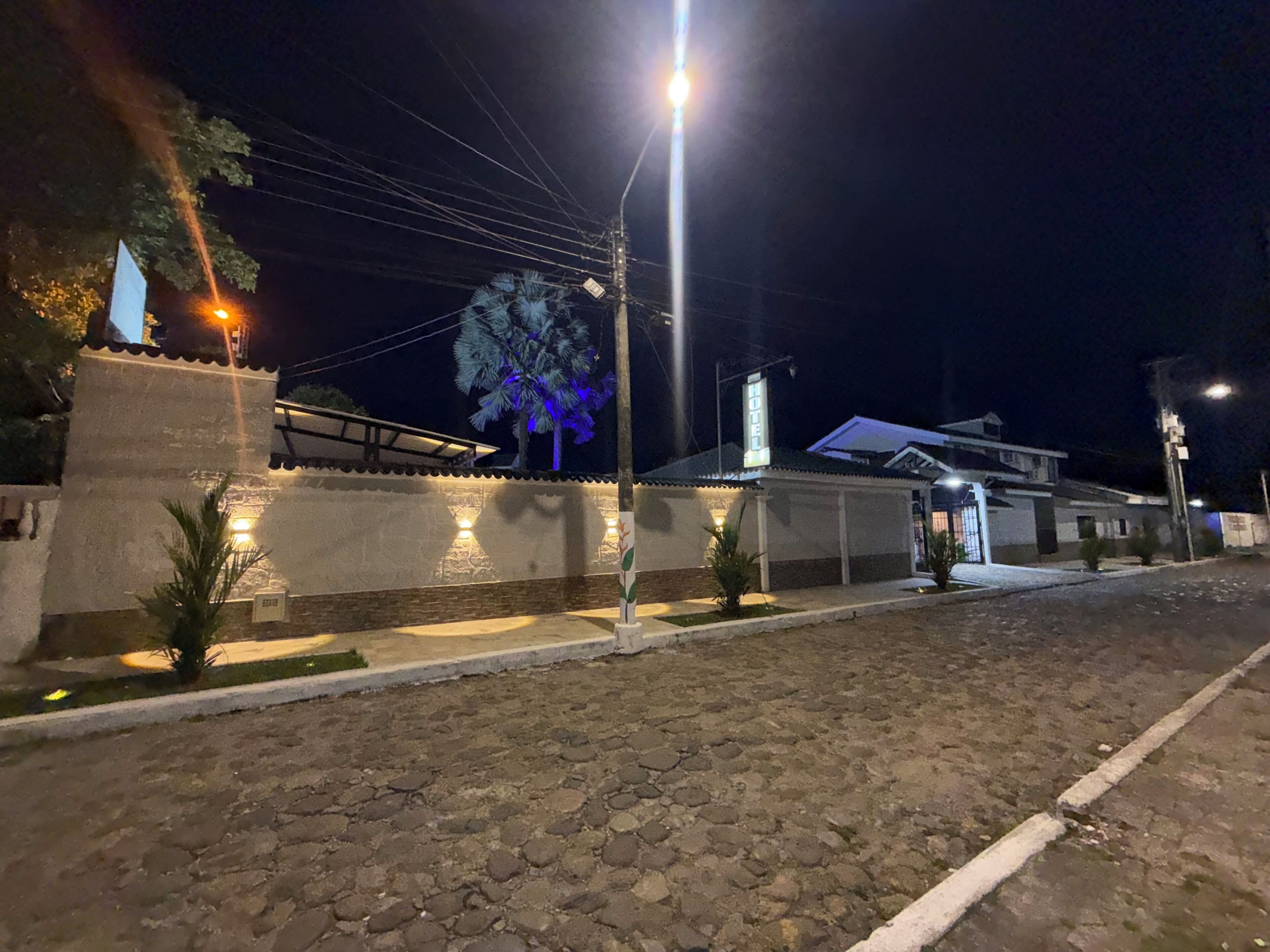 Vista nocturna de una calle con un edificio que muestra un letrero que dice "HOTEL".
