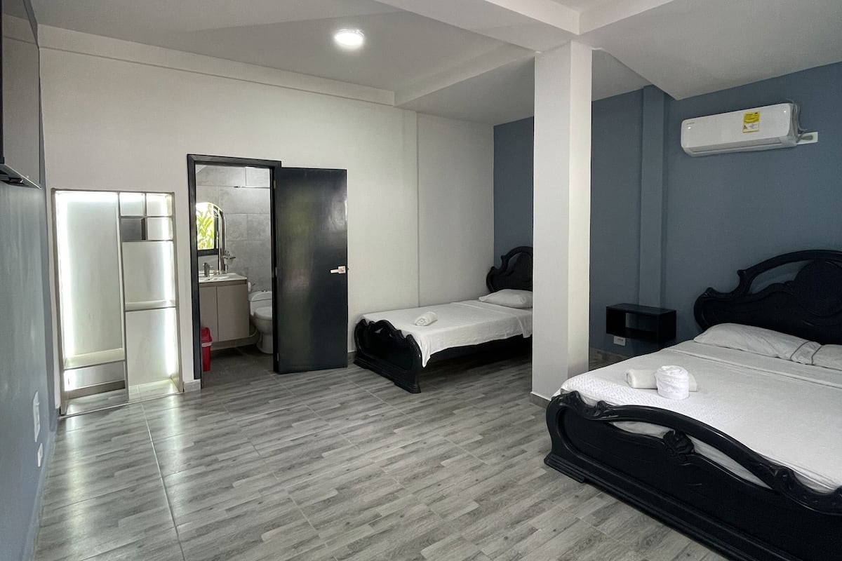 Une chambre moderne avec deux lits, une salle de bain et un coin cuisine.