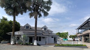 A two-story building with a tiled roof, a covered patio area, and a pool.