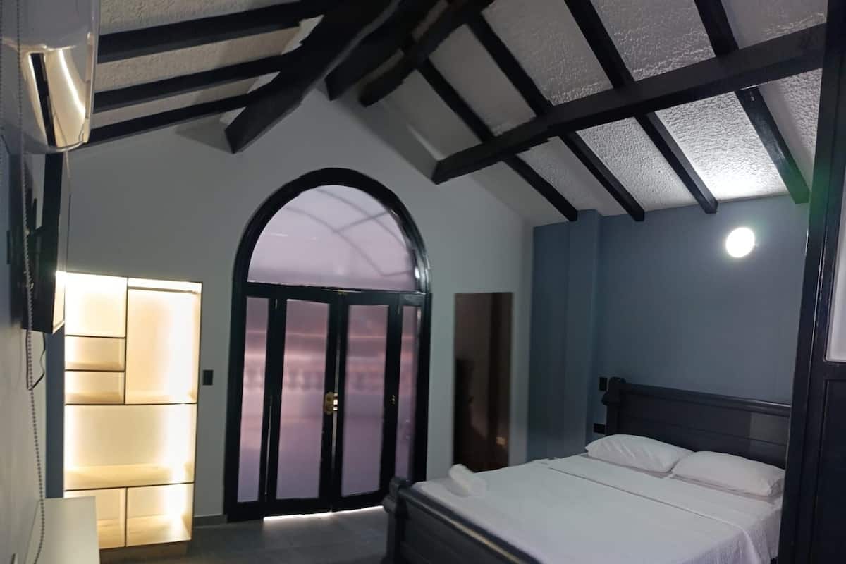 Une chambre à coucher avec un lit, une porte et un luminaire fixé au mur.