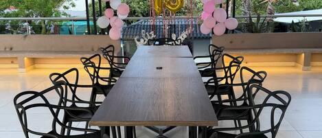 A long dining table with black chairs, surrounded by a decorative arch of pink and white balloons, and a golden '15' balloon.