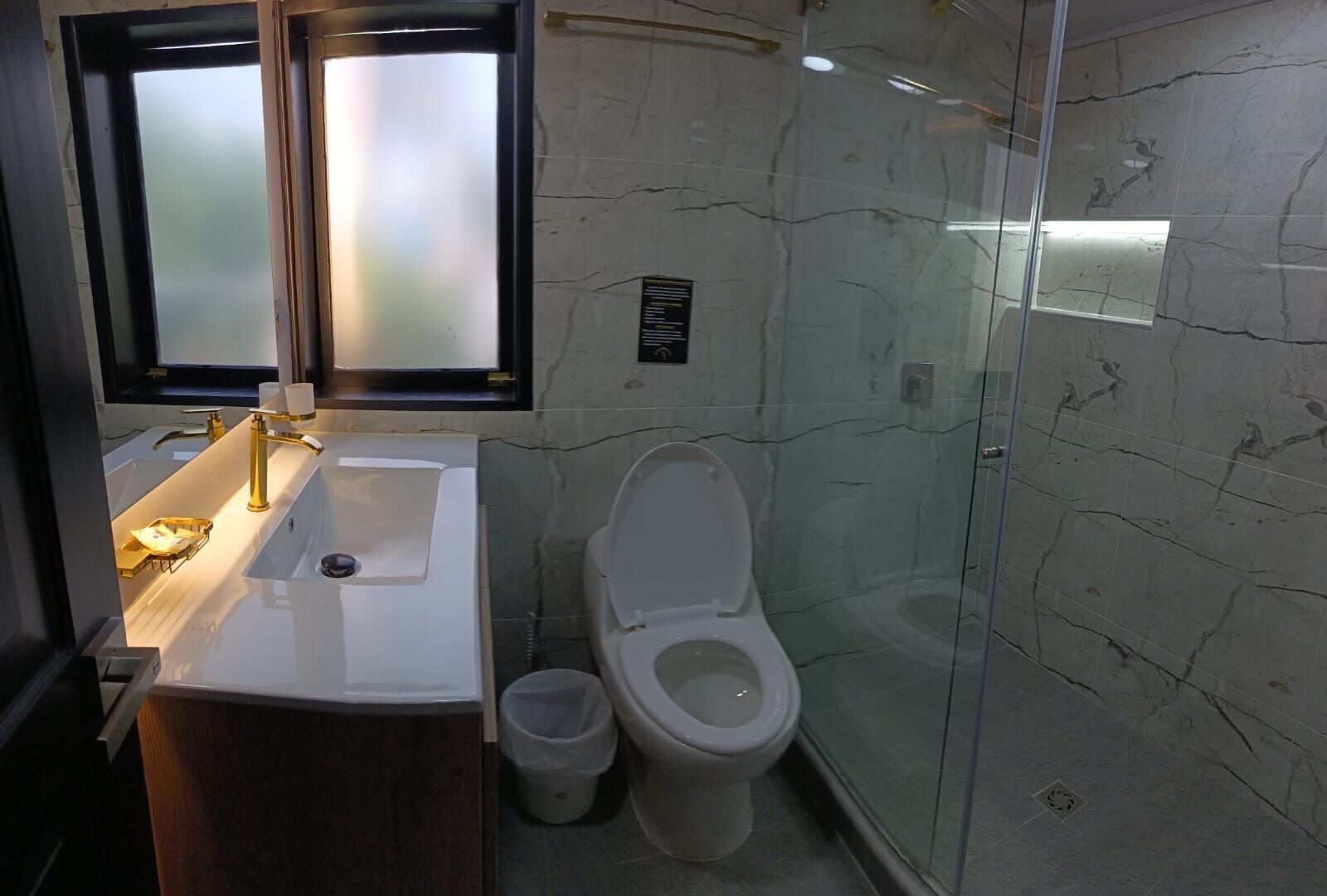 A bathroom with a white sink, a toilet, and a glass shower enclosure.