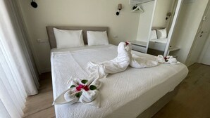 A neatly made bed with white linens and towels arranged in a decorative manner, a bedside mirror, and a simple, clean room design. - VILLA ALTUN 1 (Mugla)