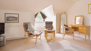 Une chambre moderne dotée d’une grande fenêtre, d’un bureau, de deux chaises, d’une télévision et d’un miroir.