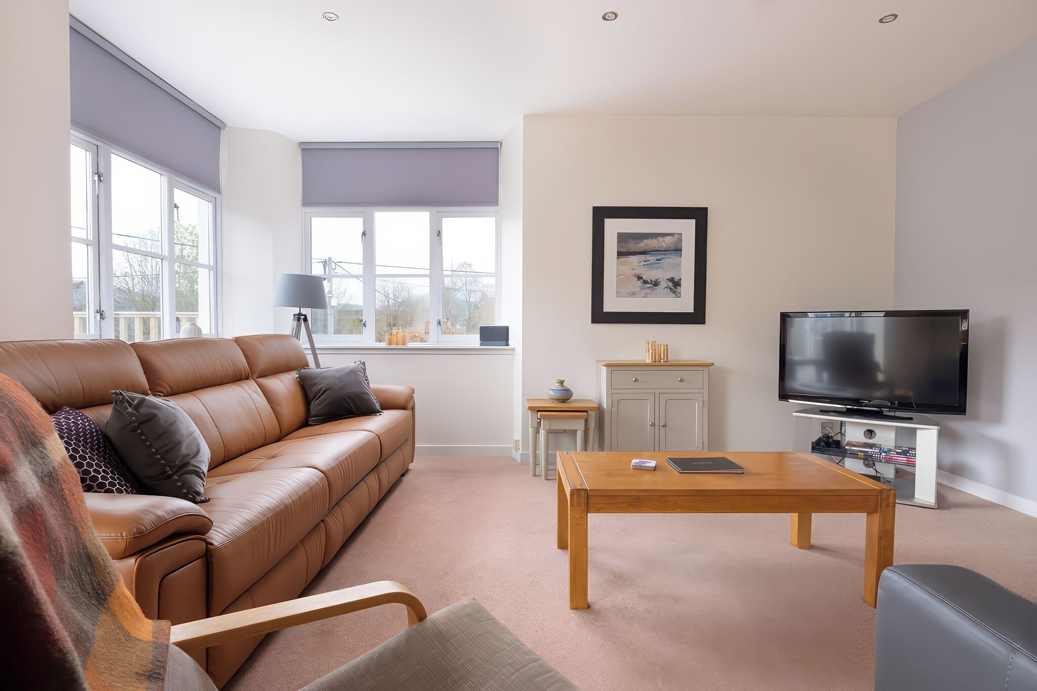 Een moderne woonkamer met een leren bank, een houten salontafel en een flatscreen televisie.