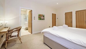 Une chambre à coucher avec un lit, un bureau et une chaise. On peut apercevoir une salle de bain à travers une porte ouverte.