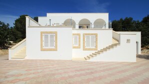 A modern white building with a hexagonal patterned floor, a staircase, and a balcony.