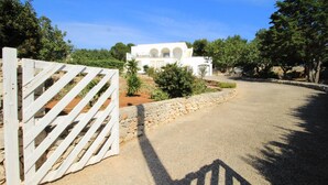 A white building with arched windows and a stone pathway leading to a gated entrance.