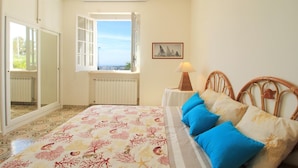 A bedroom with a bed, a window, a radiator, and a picture on the wall.