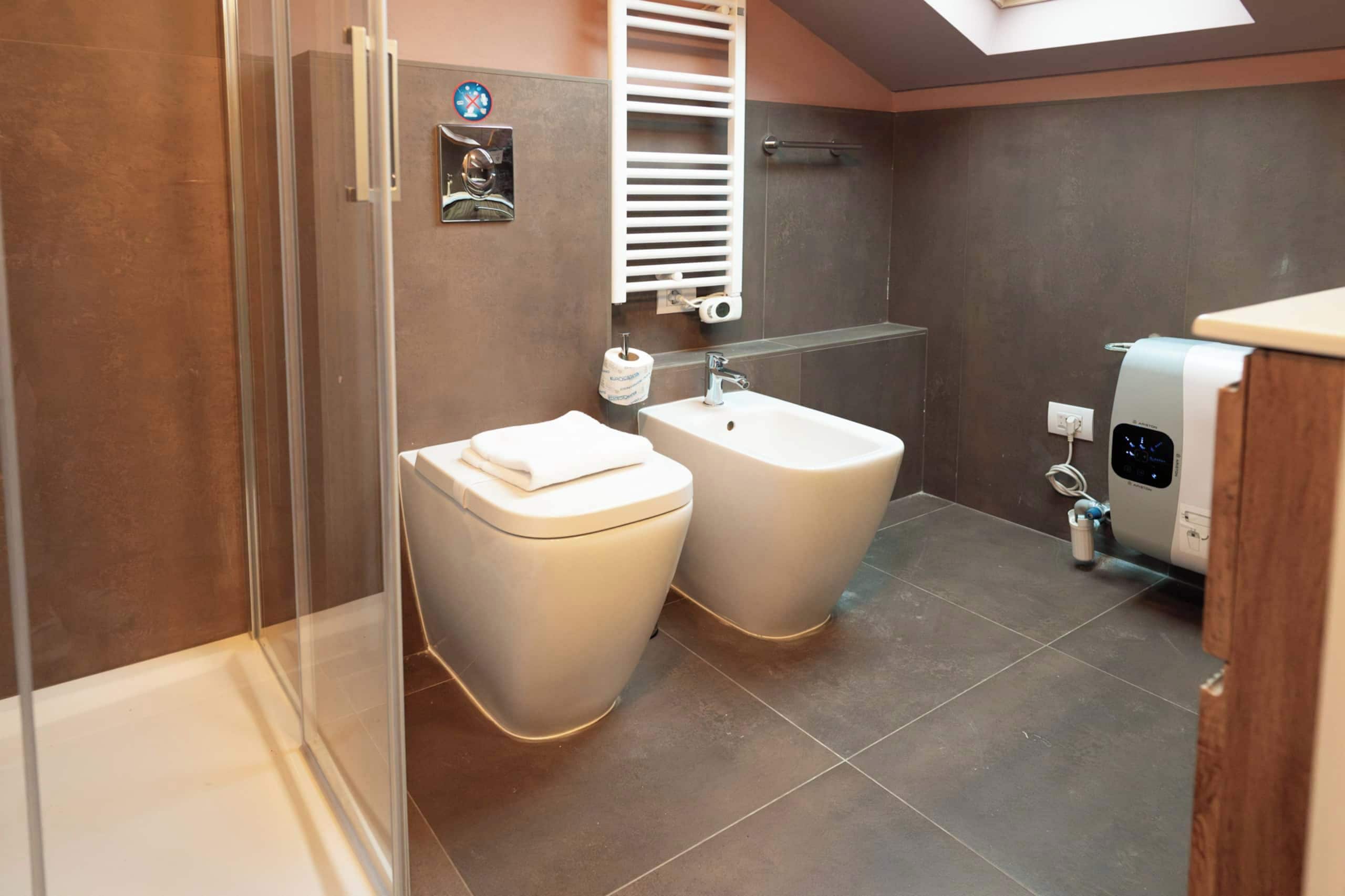 A modern bathroom with a glass shower enclosure, a toilet, a bidet, and a sink.