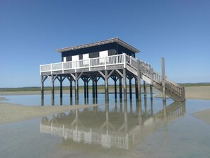 A wooden pier structure with a balcony and a small building on top, extending over a reflective water surface. - Large, charming house in L'ETALE, Meyran/La Hume (Gujan-Mestras)