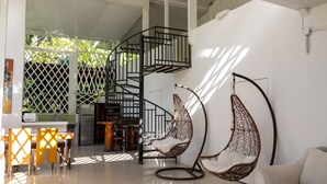 A modern interior with a spiral staircase, hanging chairs, and a dining area with a view of the outdoors.